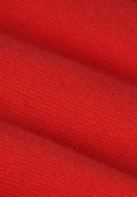 Tissu rouge avec une texture douce et un motif en relief, affichant une couleur lisse et uniforme ainsi qu'un léger éclat. Convient à diverses applications textiles.