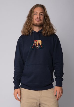 Manteau à capuche bleu marine avec une poche avant et un cordon de serrage. Présente un design de cartoon d'un personnage de hot-dog faisant du vélo.