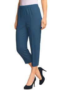 Teal gecropte broek met een losse pasvorm, elastische tailleband en verticale ribbeltextuur, gecombineerd met zwarte suède hoge hakken.