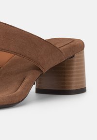 Ταμπά σανδάλι mule από σουέτ με φαρδιά λουρίδα, επενδεδυμένη σόλα και τακούνι τύπου block με μαύρο περίγραμμα στη σόλα.