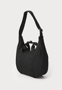Sac à bandoulière noir avec un extérieur en tissu doux, une forme arrondie, des poignées supérieures et une longue sangle ajustable ; dispose d'une fermeture éclair et d'un design minimaliste.