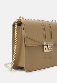 Borsa a tracolla in eco-pelle color tan con una tracolla in catena dorata, chiusura a pattina e dettagli di cucitura sottili; presenta una placca con logo metallico sul davanti.
