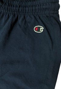 Pantaloni jogger blu navy con cintura elastica, realizzati in un tessuto morbido, caratterizzati da un piccolo logo ricamato in rosso, nero e bianco.