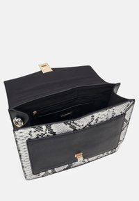 Sac à main à motif serpent noir et blanc avec fermoir doré, ouvert pour montrer la poche intérieure et le compartiment zippé, vu de dessus.