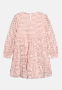 Roze jurk met lange mouwen, gestructureerde stof, gelaagde ruches en een knoopsluiting aan de achterkant. Kleine decoratieve stippen overal.