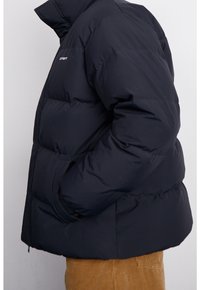Sort dunjakke med høj krave og quiltet design. Har elastiske manchetter og lynlås lukning. Enkel og funktionel form.
