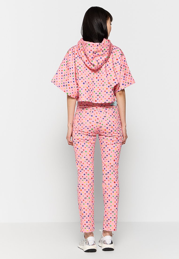 Ensemble deux pièces avec un haut court rose à motifs d'étoiles et un pantalon assorti. Comprend des imprimés colorés d'étoiles, de cœurs et de visages souriants. Coupe décontractée.