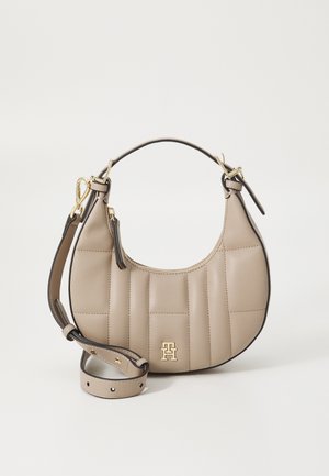 Beige nahast käekott, millel on lokkis tekstuur, kuldne riistvara ja eemaldatav rihm. Ümar kuju siledaga viimistlusega ja logoga aktsent.