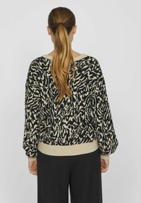 Czarny i beżowy sweter w wzory o luźnym kroju, z obszernymi rękawami i ryflowanym dołem. Gładka struktura z mieszanką kolorów.