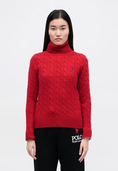 Pulover roșu cu guler înalt, tricotat într-un model cu torsade, cu tivuri și manșete cu dungi; are un mic logo brodat. Asortat cu pantaloni de trening negri.