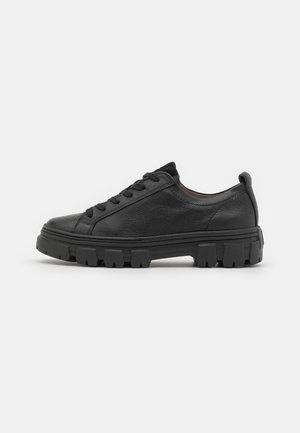 Sort lavtopet lædersneaker med tyk robust sål og sorte snørebånd, set fra siden på en ens hvid baggrund.