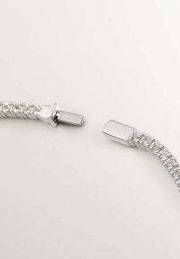 Pulsera trenzada de plata con cierres metálicos rectangulares en cada extremo. Textura suave y acabado brillante con un detalle brillante.