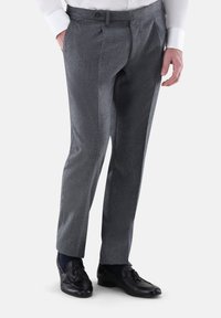 Graue, strukturierte Hose mit tailliertem Schnitt, flachem Frontdesign, seitlichen Taschen und Gürtelschlaufen. Kombiniert mit schwarzen Slippern und marineblauen Socken.