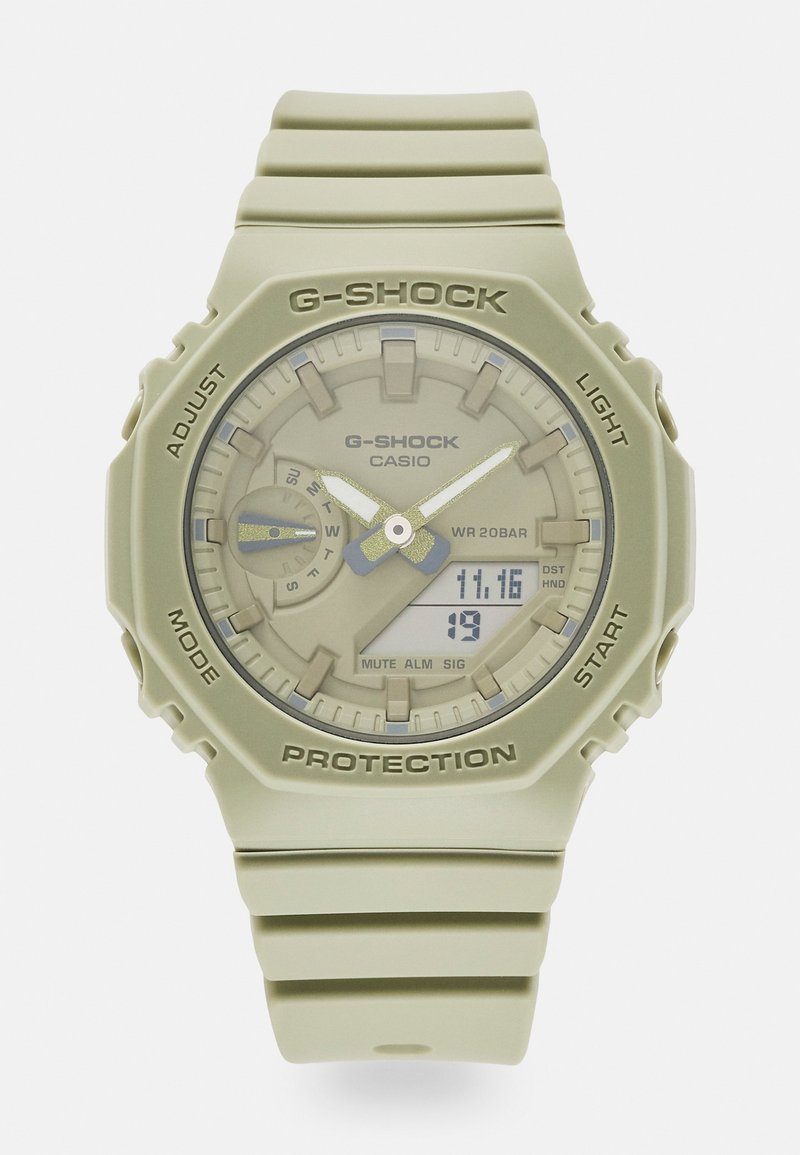 Montre Casio G-Shock beige avec affichage analogique et numérique, affichant la date et l'heure, avec des boutons étiquetés pour régler, mode, lumière et démarrer.