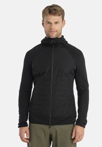 Black insulated zip-up jacket with a hood, featuring a smooth body and textured arms. Lightweight material and a slim fit design.