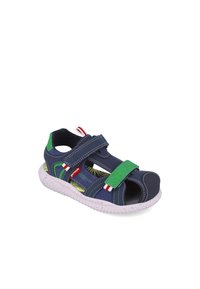 Sandalia infantil azul marino con correa verde ajustable, punta abierta y suela blanca acolchada; presenta una plantilla con un diseño de hojas.