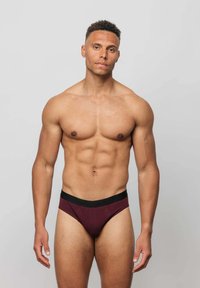 Burgunderfarbene Herrenunterhose mit einem schwarzen elastischen Bund, gefertigt aus einem weichen, dehnbarem Stoff. Verfügt über ein enganliegendes Design und minimale Nähte.