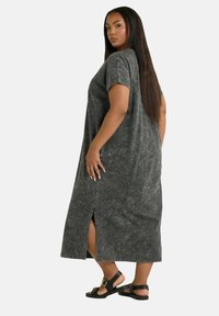 Tummanharmaa puuvillamaksimekko, jossa on rento istuvuus, lyhyet hihat, halkiot sivuilla ja pehmeä, teksturoitu pinta. Yhdistetty litteisiin sandaaleihin.
