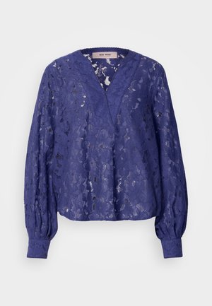 Blouse en dentelle purple avec un décolleté en V, des manches bouffantes longues et des poignets côtelés. Le tissu présente des motifs floraux et une texture translucide.