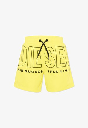 Pantalones cortos amarillos con cordón negro y texto negro grande con contorno que dice "DIESEL" y texto más pequeño "FOR SUCCESSFUL LIVING" en la parte delantera.