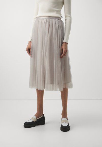 Gonna midi in tulle leggera color grigio chiaro, con vita elastica. Abbinata a mocassini platform bianchi e neri.