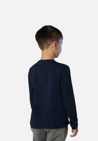 Camisa de manga larga azul marino de algodón, con cuello redondo y dobladillo recto, exhibida desde la parte de atrás en un niño.
