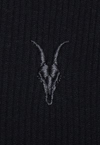 Schwarzer Strickstoff mit einem auffälligen gestickten Ziegenschädel-Design in Dunkelgrau, mit feiner Ripptextur im gesamten Material.