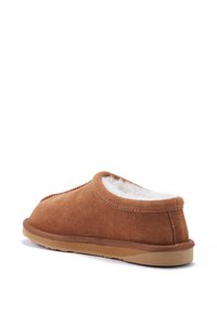 Brown suede slipper with a soft, white fur lining. Rounded design and low back, featuring a rubber sole for durability and comfort.
