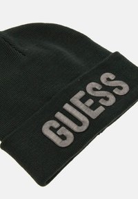 Berretto di maglia nero con risvolto, caratterizzato dalla parola "GUESS" ricamata in grigio sul davanti, con una texture liscia.
