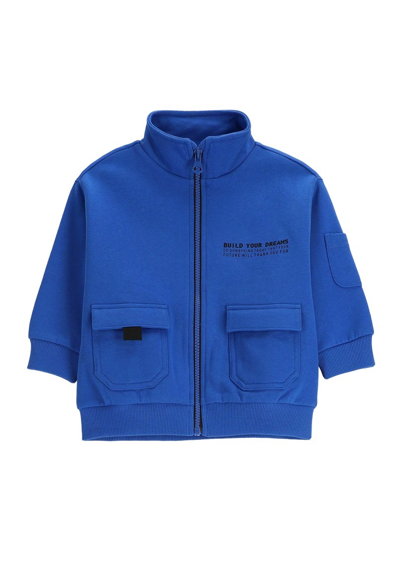Niebieska kurtka zapinana na zamek z wysokim kołnierzem, dwoma przednimi kieszeniami, ściągaczami przy mankietach oraz nadrukowanym tekstem po lewej stronie. Wykonana z miękkiego, elastycznego materiału.