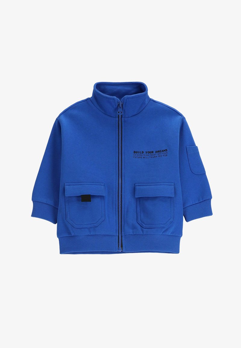 Niebieska kurtka zapinana na zamek z wysokim kołnierzem, dwoma przednimi kieszeniami, ściągaczami przy mankietach oraz nadrukowanym tekstem po lewej stronie. Wykonana z miękkiego, elastycznego materiału.