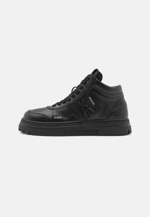 Zapatilla negra de caña alta con suela gruesa, cordones, diseño de abeja en relieve, texto "LET ME FLY" y collarín acolchado en el tobillo.
