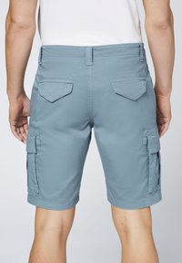 Shorts cargo pour hommes en tissu bleu clair, dotés de deux poches arrière et de poches cargo latérales, avec une coupe droite et un ourlet au-dessus du genou.