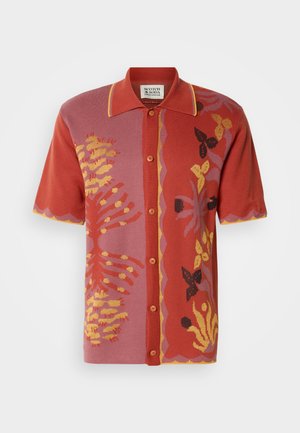Koszula z krótkim rękawem w odcieniach czerwieni i różu, z kwiatowymi wzorami oraz akcentami w kolorach żółtym i czarnym. Przód zapinany na guziki z kontrastującym kołnierzem.