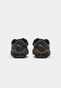 Pantofi sport maronii cu talpă din cauciuc negru, parte superioară texturată și un design rear distinctiv cu un logo gri. Fără șireturi vizibile.