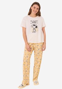 Witte T-shirt met korte mouwen en een Snoopy-graphic, gecombineerd met gele pyjamabroek met Snoopy-patronen. Zachte stof en een relaxte pasvorm.