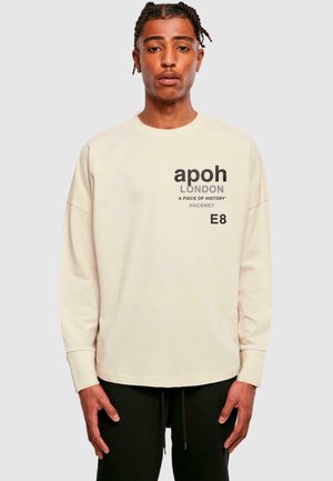 Light beige long-sleeve sweatshirt with black graphic text; soft cotton material, relaxed fit, crew neck, and ribbed cuffs.