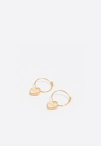 Pendientes de aro dorados con pequeños encantos en forma de corazón. Los encantos en forma de corazón tienen un acabado suave y grabados en un lado, añadiendo detalle.