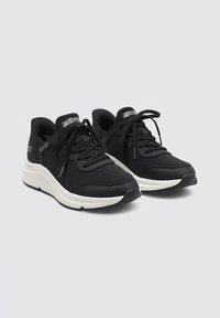 Schwarze Sportschuhe mit einem Obermaterial aus Mesh, Schnürdesign und Gummisohle. Verfügt über eine weiße Zwischensohle und das Skechers-Logo an der Seite.