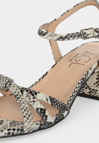 Γυναικεία σανδάλια με ανοιχτή μύτη, λουριά με μοτίβο φίδι, αγκράφα στο αστράγαλο, τακούνι τύπου block και μπεζ πέλμα με ετικέτα «AGL.»