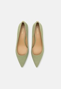 Pump in suede verde con punta affusolata, design elegante, apertura sul retro e un piccolo dettaglio in oro sul tacco. Fodera interna liscia.