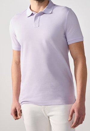 Licht lavendelkleurig poloshirt van glad katoen, met een kraag, twee knopen aan de voorkant en korte mouwen. Draagt wit broek.