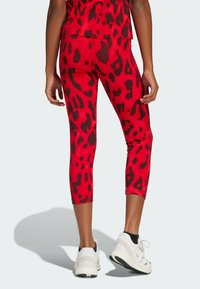 Leggings capri rojos con un estampado de leopardo negro. Confeccionados en una tela elástica con una textura suave, presentan un diseño de cintura alta.