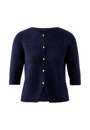 Cardigan court bleu marine à manches courtes en tissu duveteux, avec cinq petits boutons blancs sur le devant et un col rond.