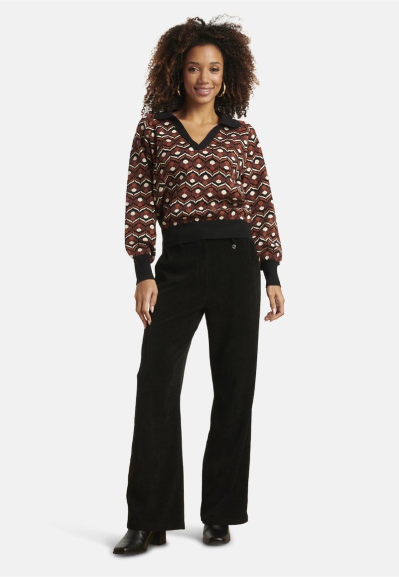 Sweater with geometric pattern in brown, cream, and black; V-neck and ribbed cuffs. Black corduroy wide-leg pants; ankle-height black boots.