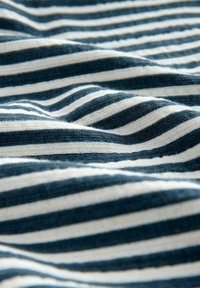 Tkanina w paski z przemiennymi ciemnoniebieskimi i białymi paskami, o miękkiej teksturze i subtelnym wzorze fal. 