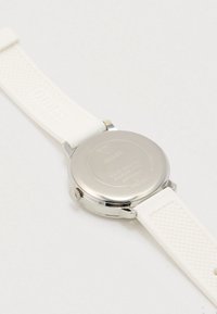 Hvid silikonrem ur med rundt sølvfarvet rustfrit stål urkasse, graveret bagside og tekstureret rem for bedre greb. Vandafvisende funktion bemærket.