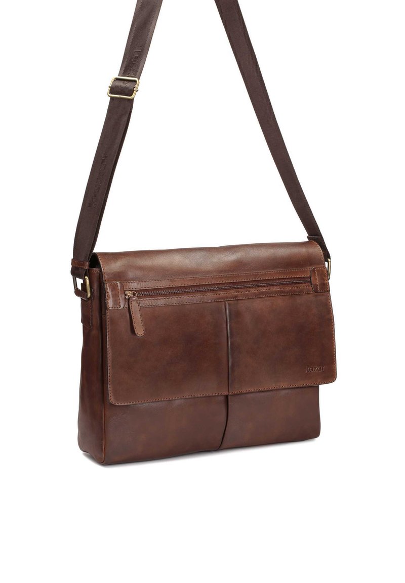 Borsa a tracolla in pelle marrone con tracolla regolabile, tasca frontale con zip e copertura a patta con due scomparti frontali. Texture liscia.