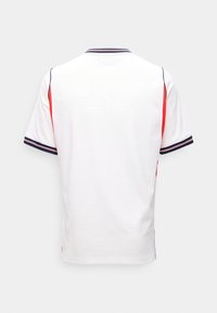 Wit shirt met korte mouwen met marineblauwe en rode streepaccenten op mouwen en kraag, van achteren getoond tegen een effen achtergrond.