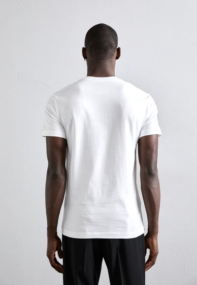 Tricou alb din bumbac, cu mâneci scurte, de tip crew neck și o croială lejeră, având o textură netedă și detalii minime pe spate.